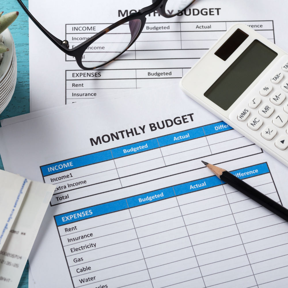 paper with table for monthly budgeting, calculator, and glasses